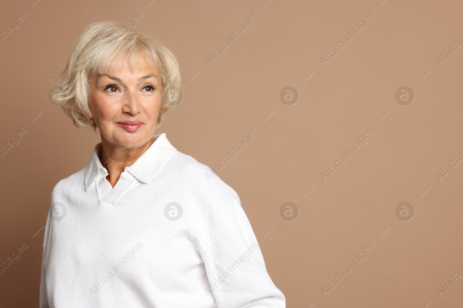 Photo of Portrait of beautiful senior woman on light brown background, space for text