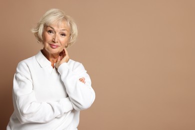 Photo of Portrait of beautiful senior woman on light brown background, space for text