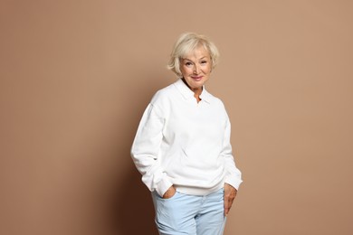 Portrait of beautiful senior woman on light brown background