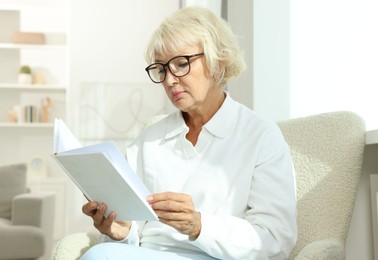 Photo of Beautiful senior woman reading book at home