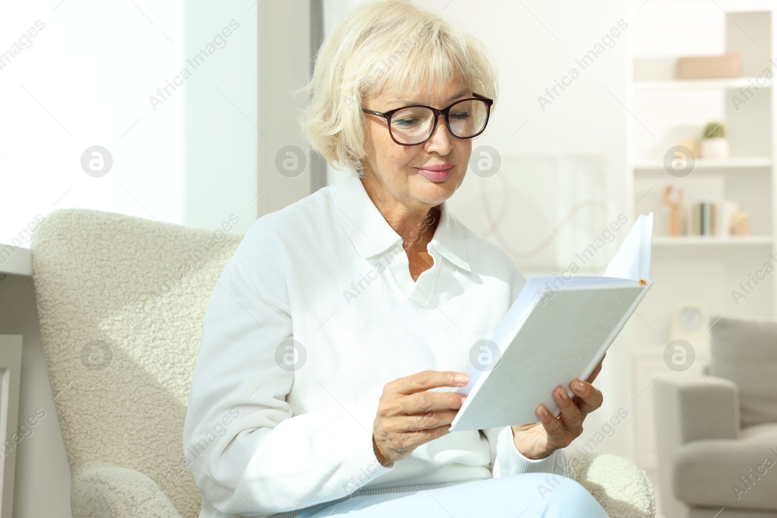 Photo of Beautiful senior woman reading book at home