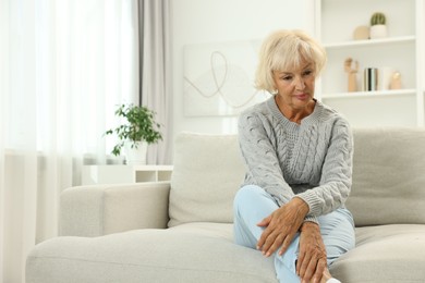 Photo of Beautiful senior woman sitting on sofa at home, space for text