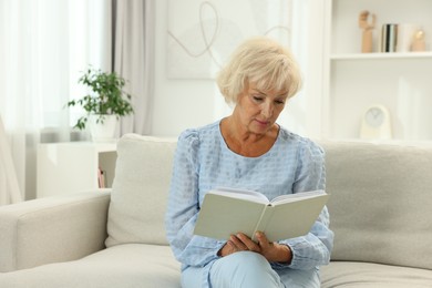 Photo of Beautiful senior woman reading book at home