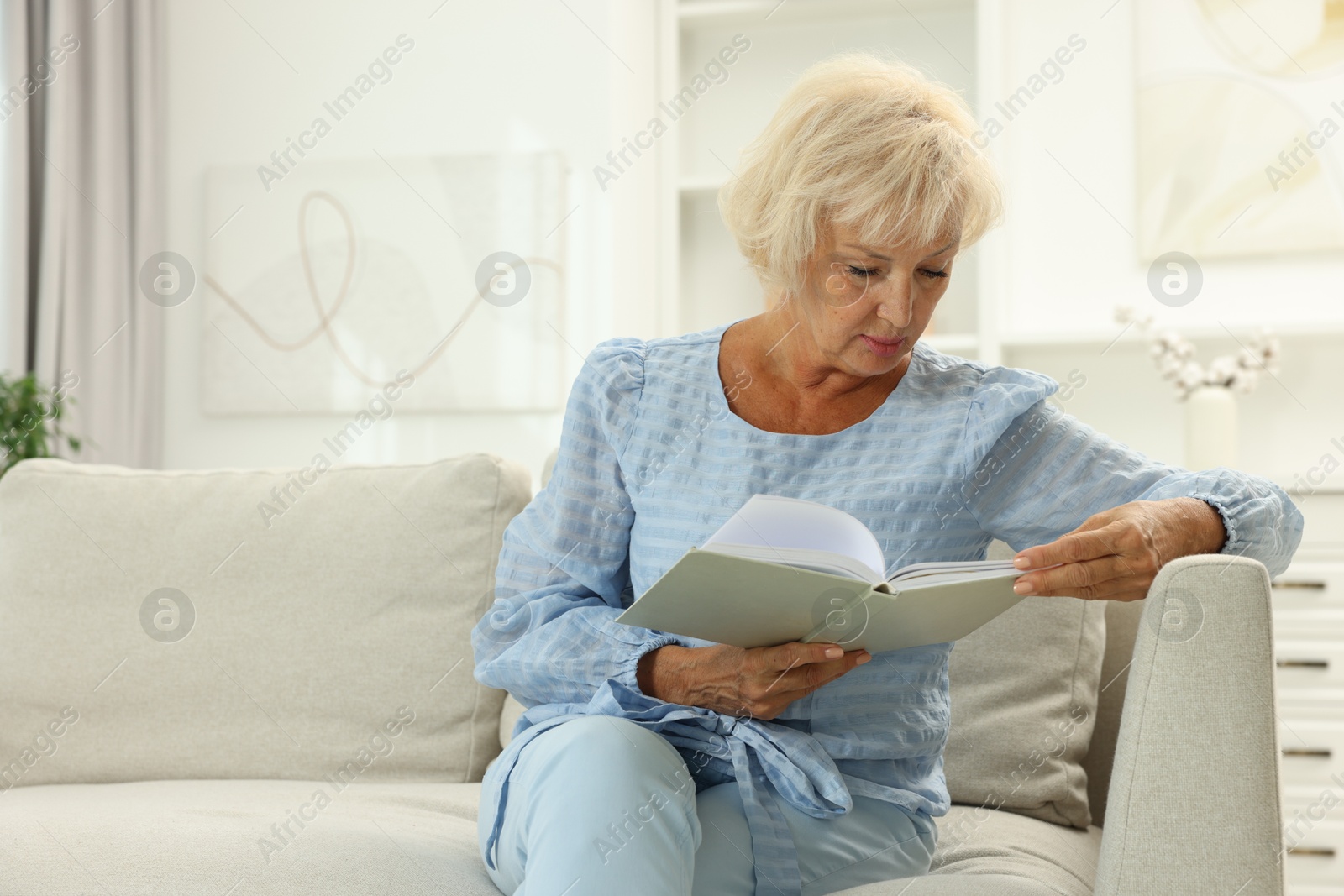 Photo of Beautiful senior woman reading book at home