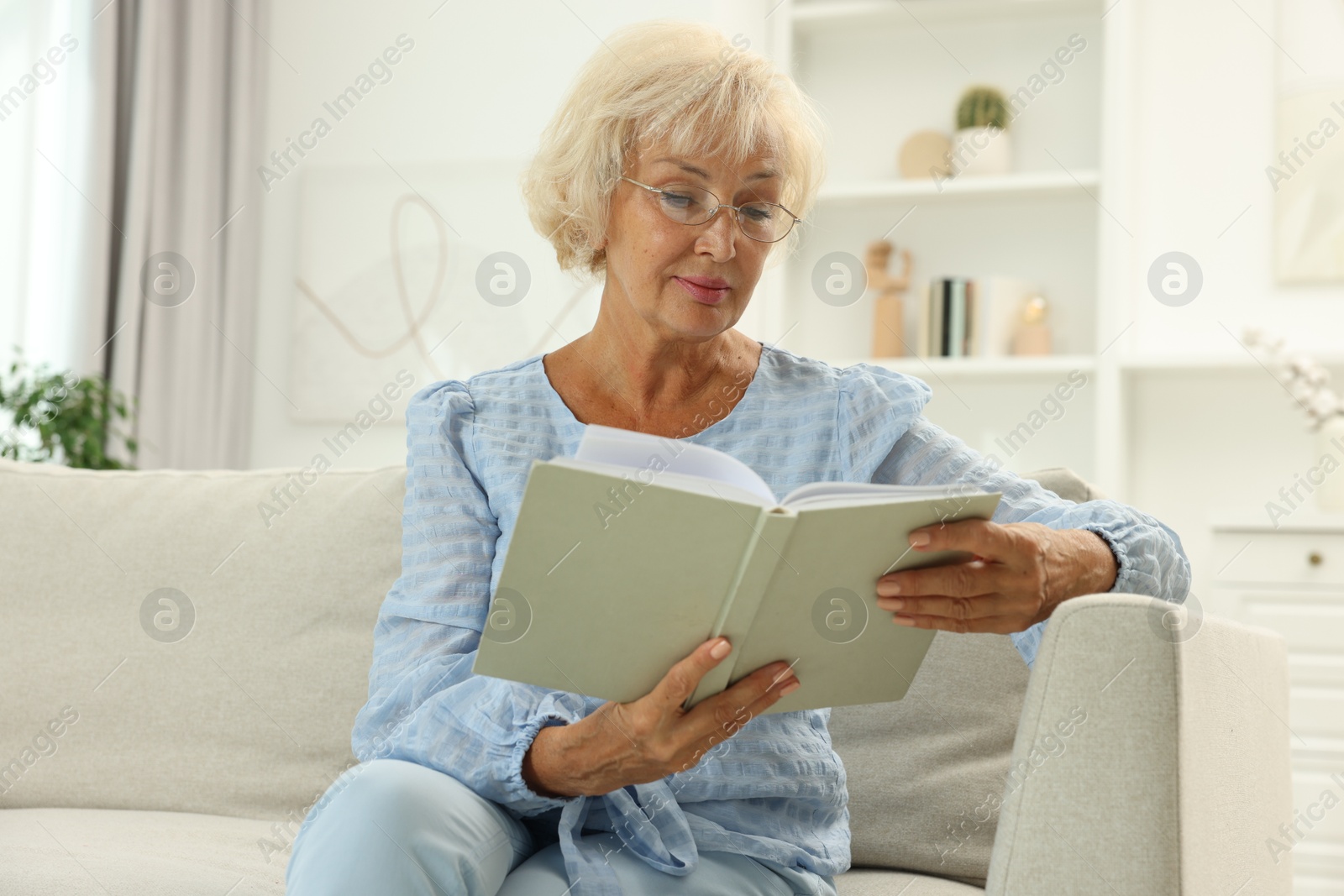 Photo of Beautiful senior woman reading book at home