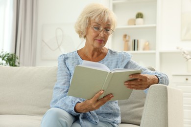 Photo of Beautiful senior woman reading book at home