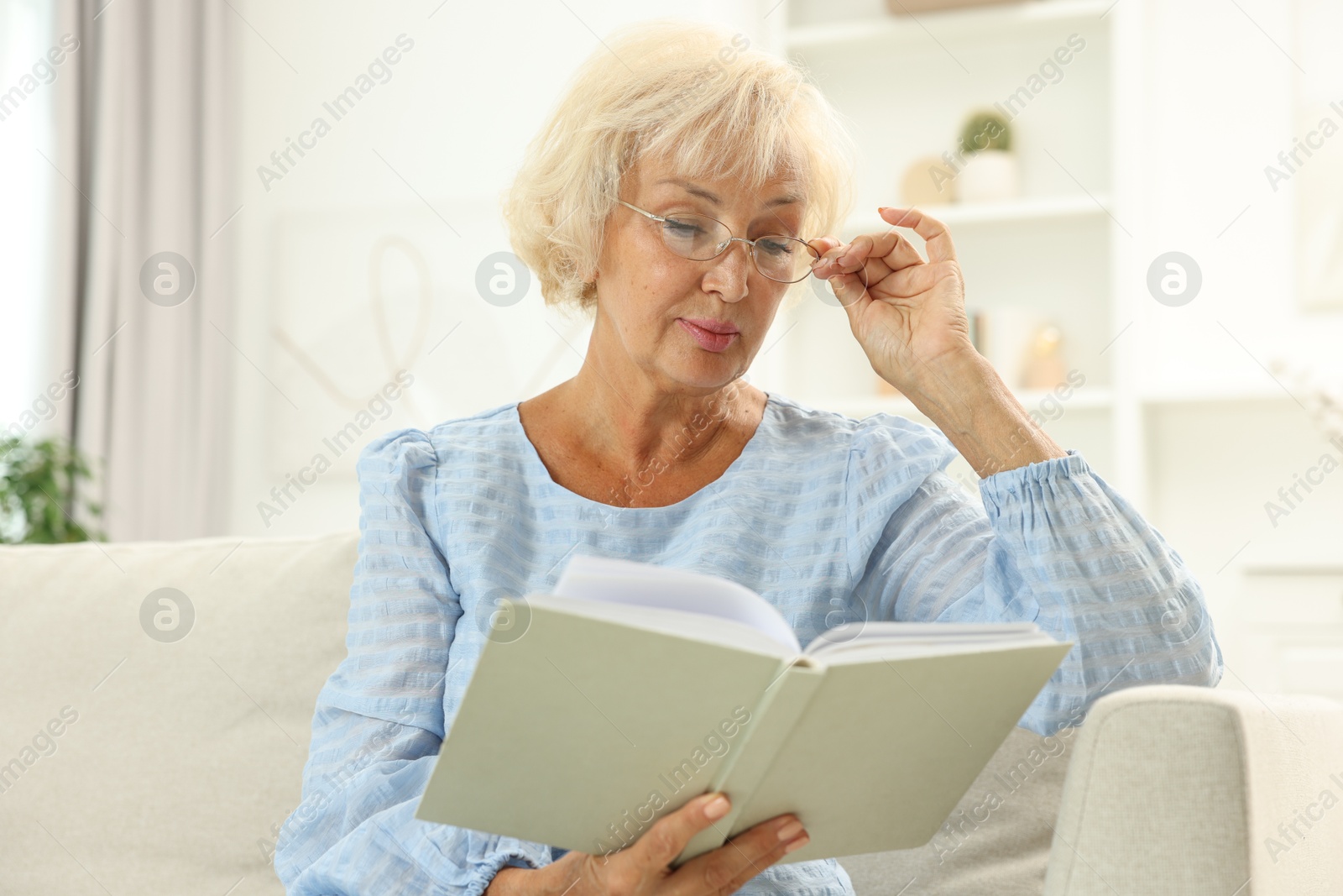 Photo of Beautiful senior woman reading book at home