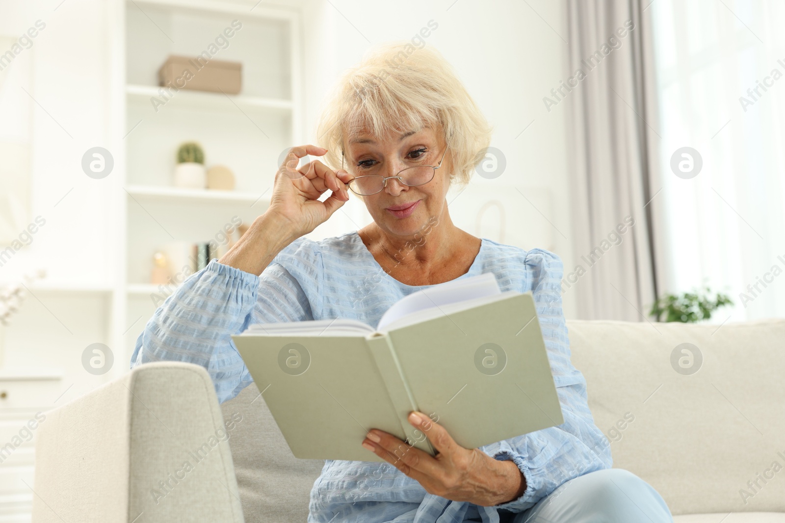 Photo of Beautiful senior woman reading book at home