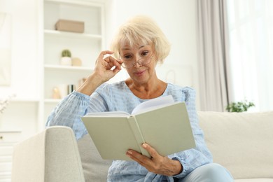 Photo of Beautiful senior woman reading book at home