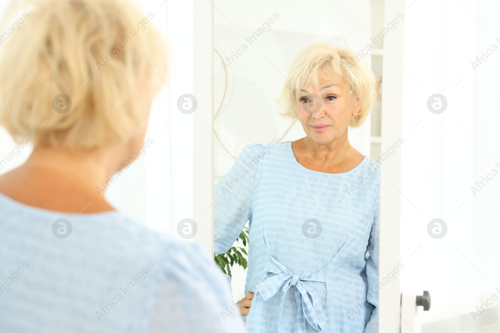 Photo of Beautiful senior woman near mirror at home