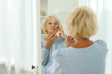 Photo of Beautiful senior woman near mirror at home