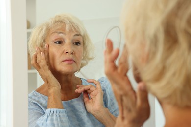 Photo of Beautiful senior woman near mirror at home