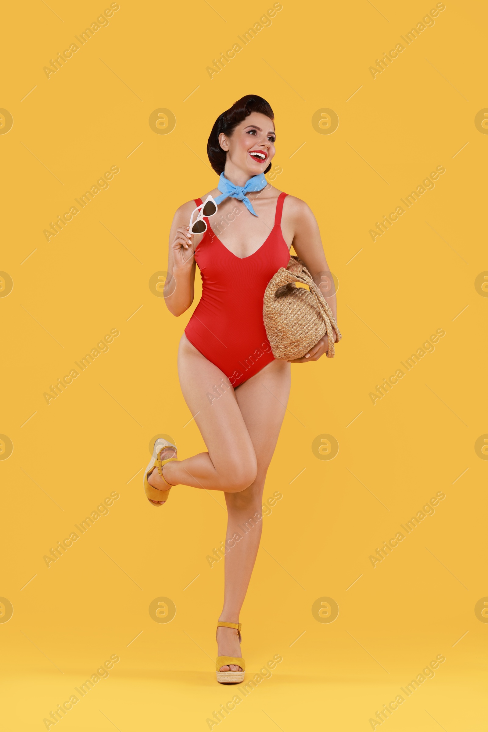 Photo of Pin-up woman in swimsuit with beach bag on orange background