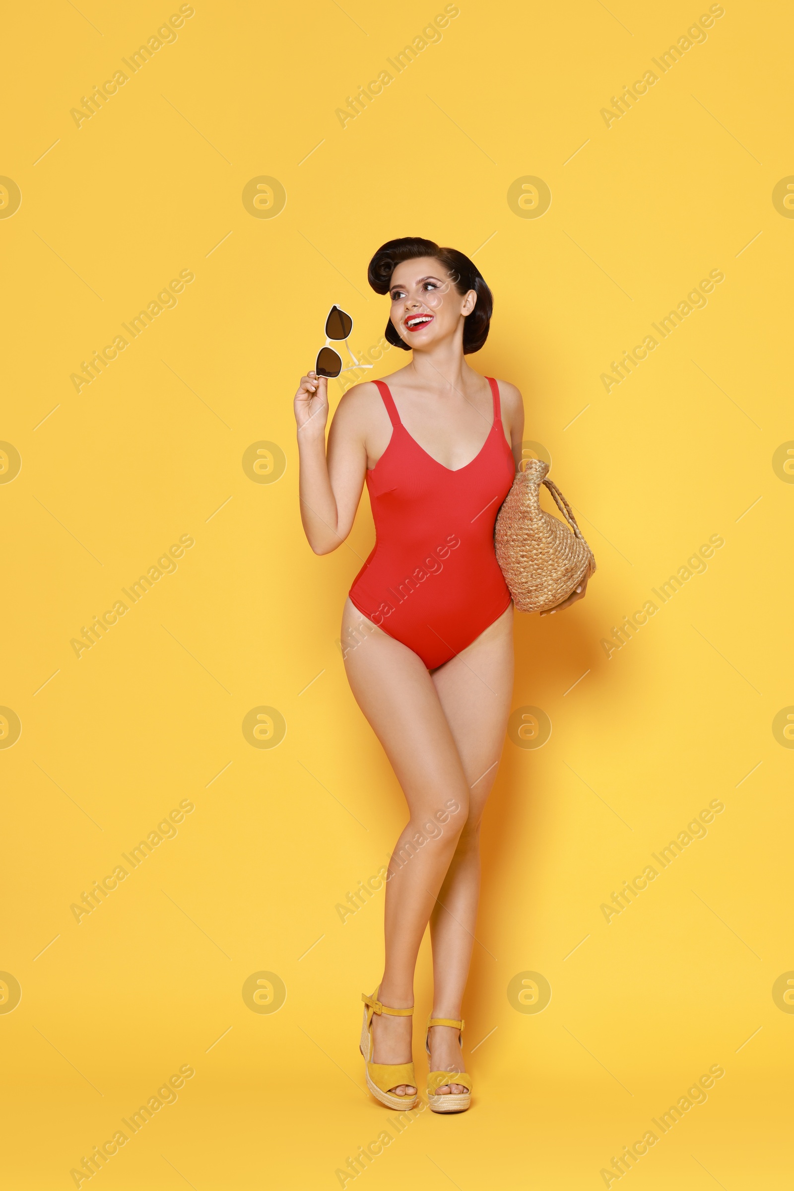 Photo of Pin-up woman in swimsuit with beach bag on orange background