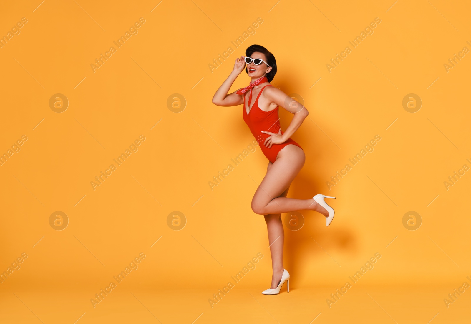 Photo of Pin-up woman in swimsuit on orange background, space for text