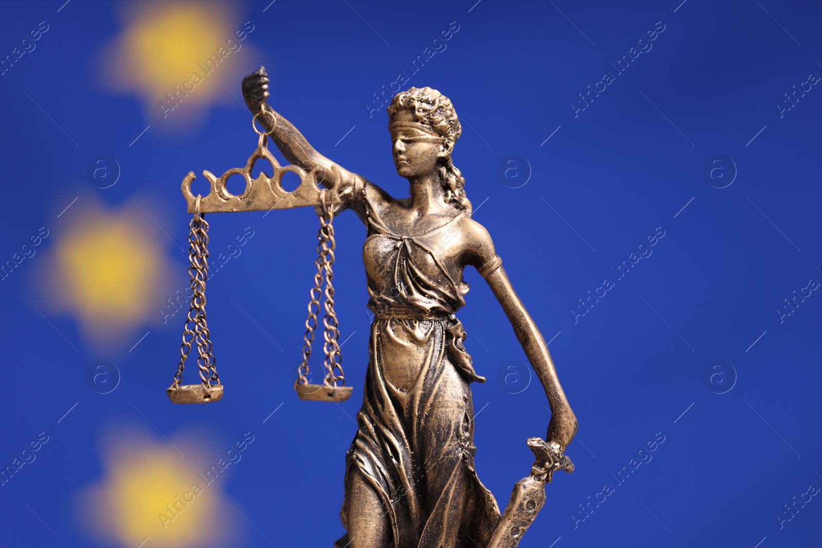 Photo of Figure of Lady Justice against European Union flag, closeup