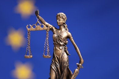 Figure of Lady Justice against European Union flag, closeup