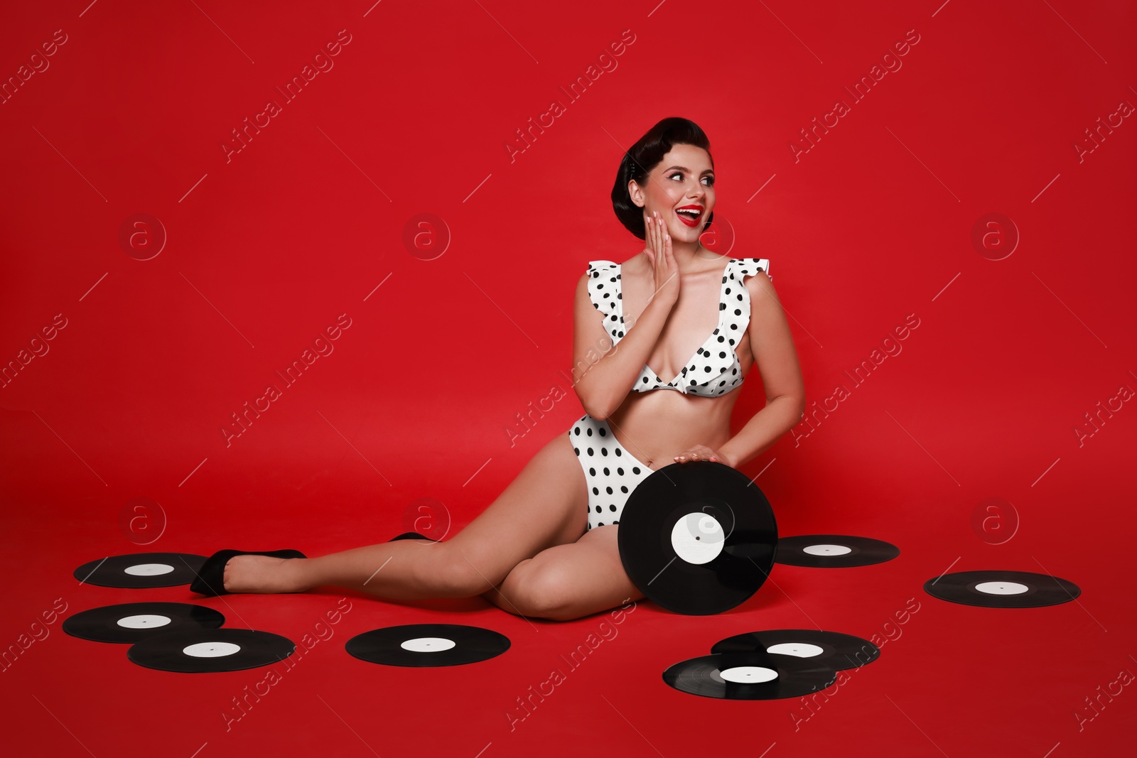 Photo of Pin-up woman in bikini with vinyl records on red background