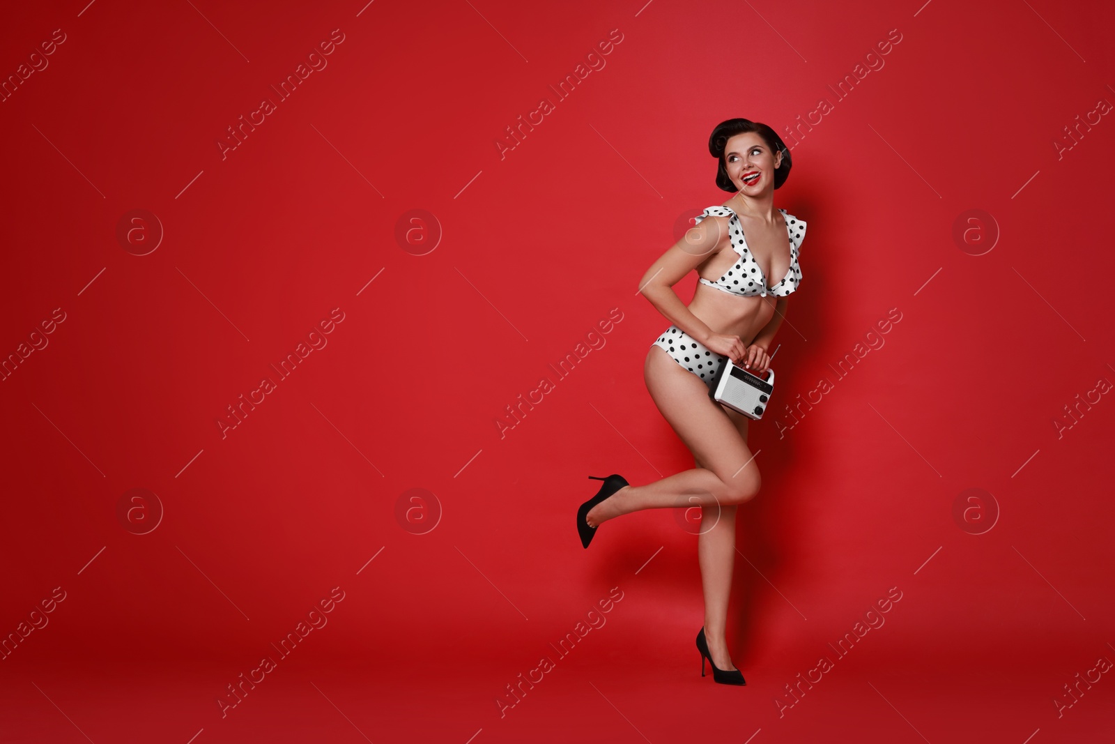 Photo of Pin-up woman in bikini with radio receiver on red background, space for text