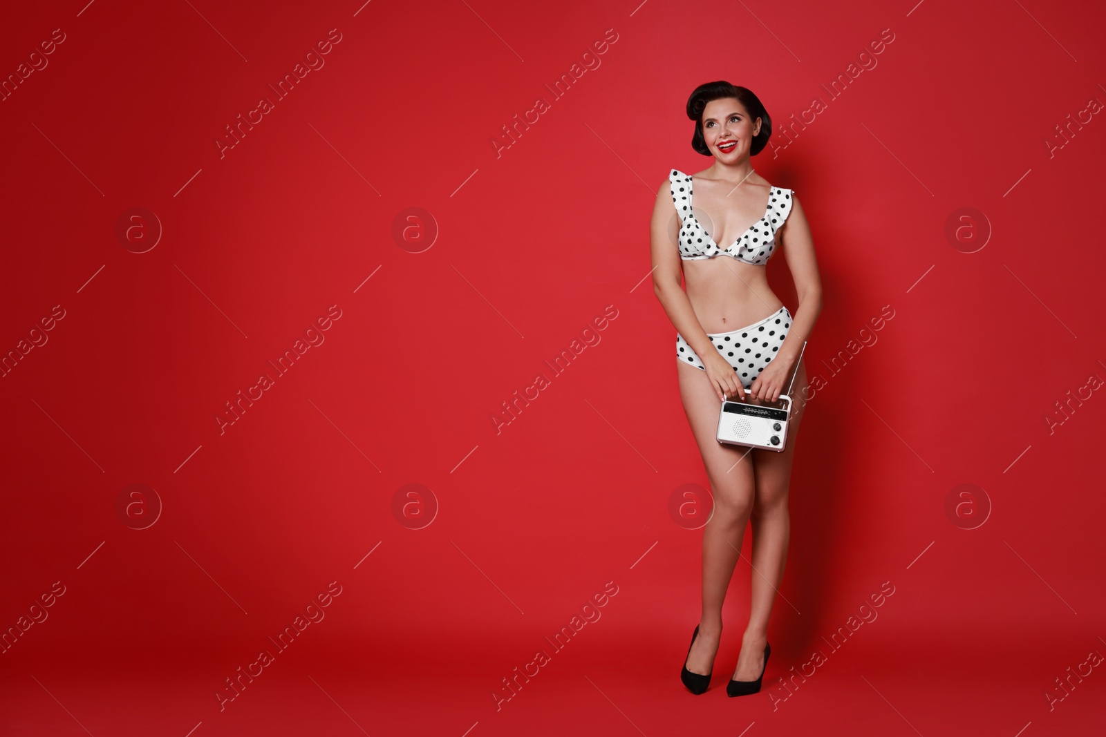 Photo of Pin-up woman in bikini with radio receiver on red background, space for text