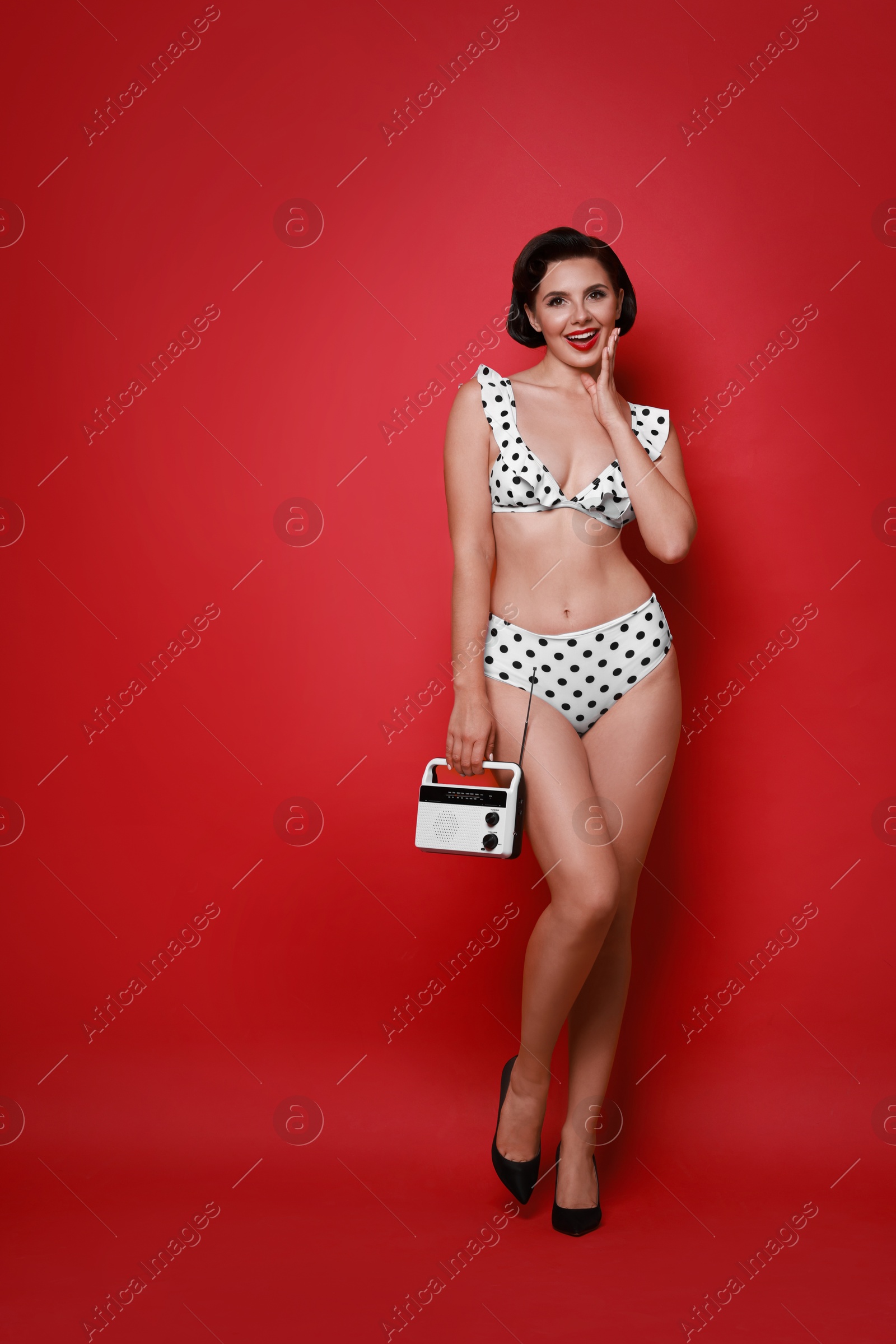 Photo of Pin-up woman in bikini with radio receiver on red background, space for text