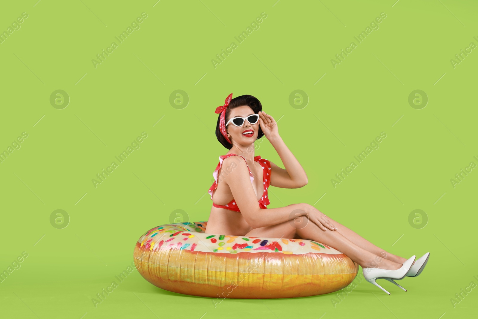 Photo of Pin-up woman in bikini with inflatable ring on green background