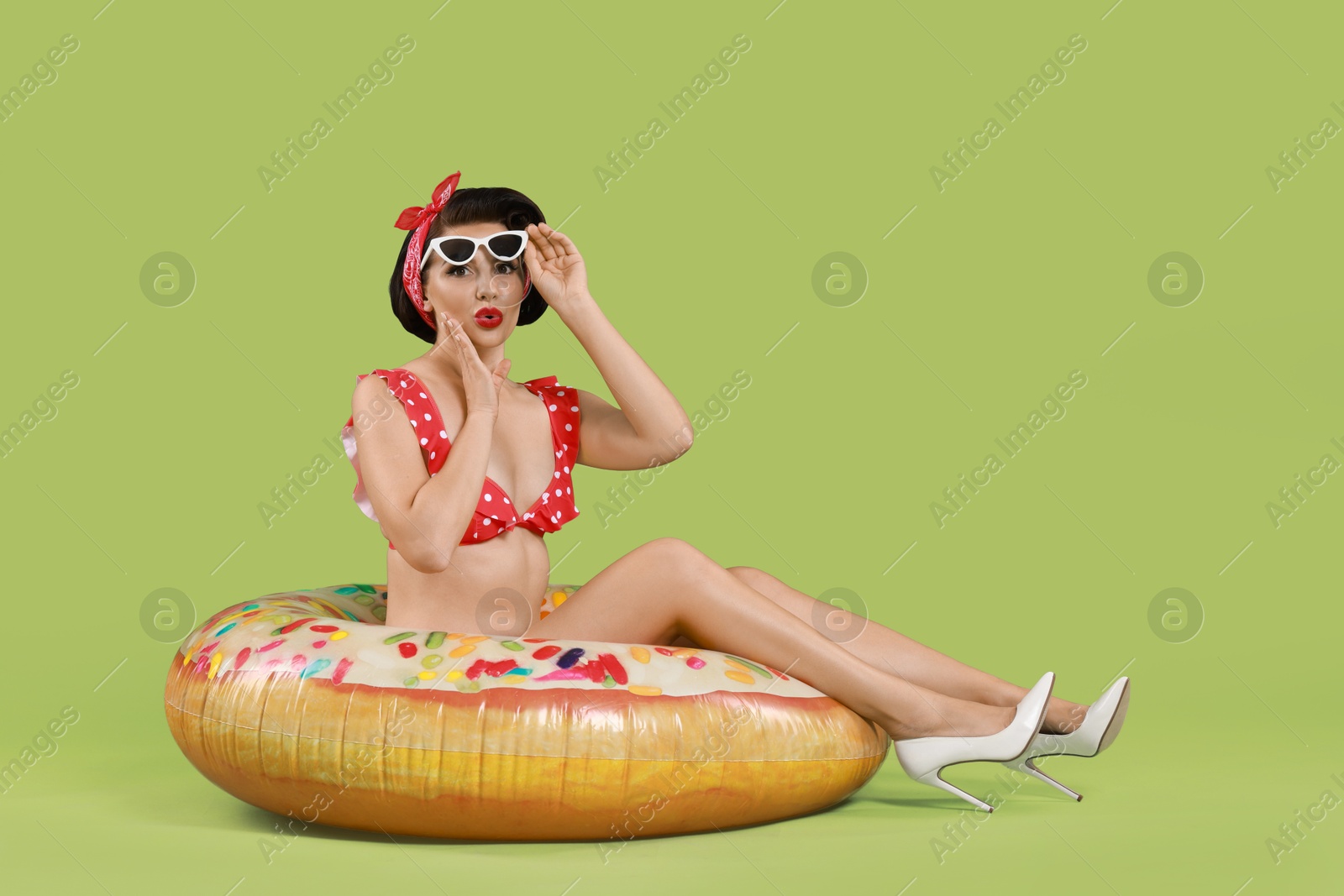 Photo of Pin-up woman in bikini with inflatable ring on green background