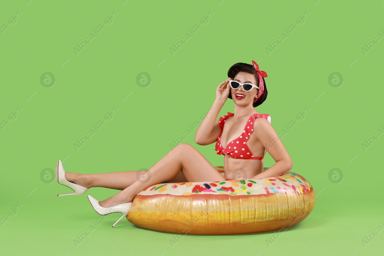 Photo of Pin-up woman in bikini with inflatable ring on green background