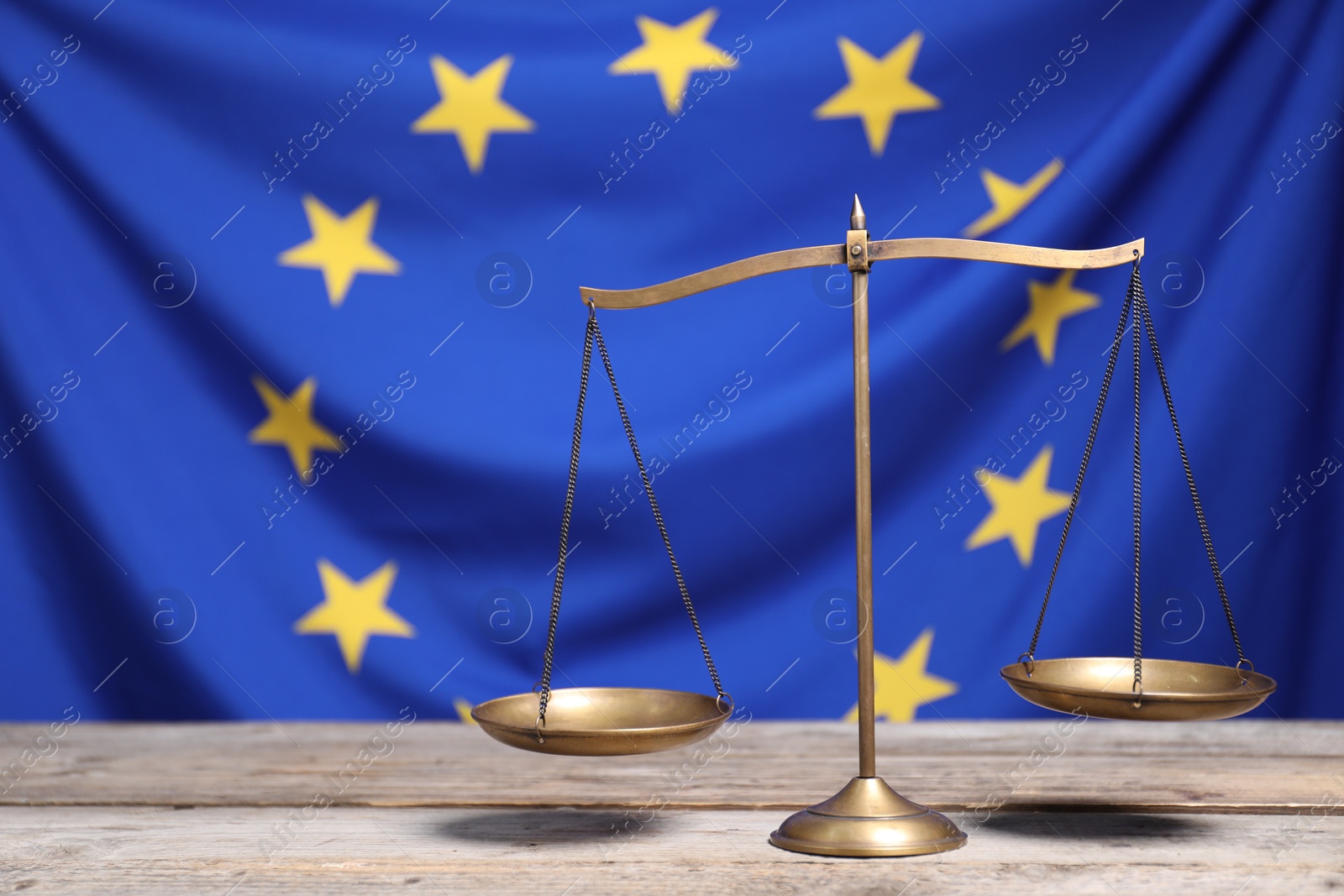 Photo of Scales of justice on wooden table against European Union flag, space for text