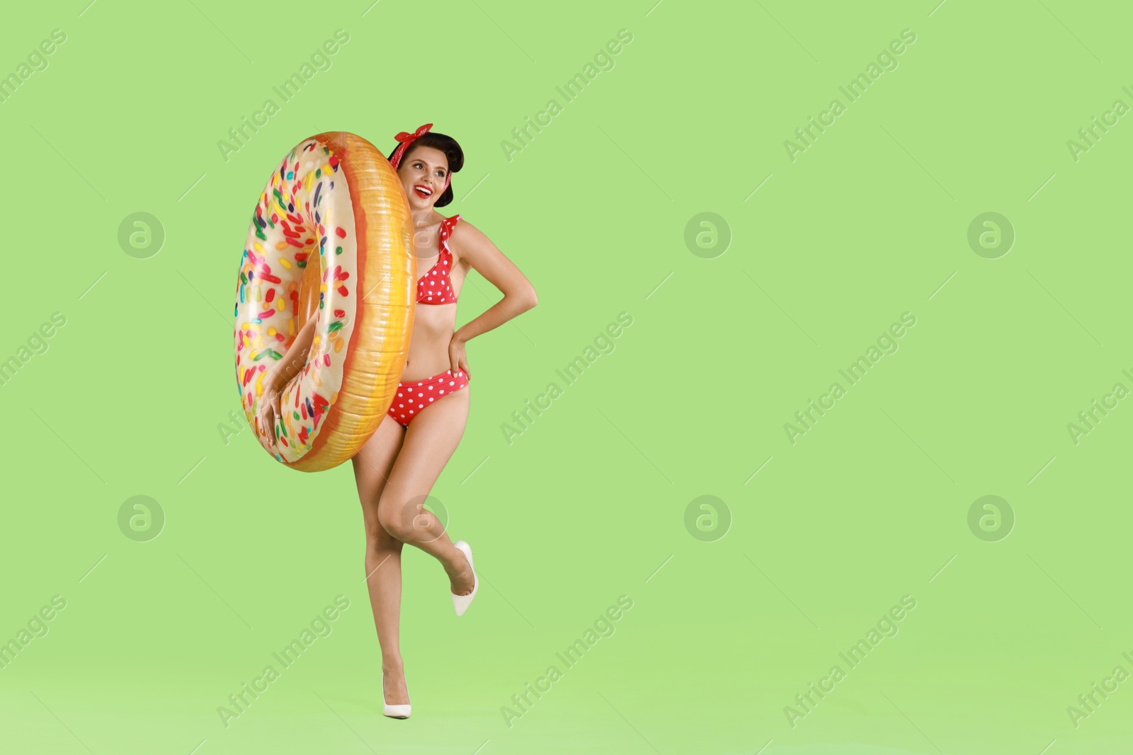 Photo of Pin-up woman in bikini with inflatable ring on green background, space for text