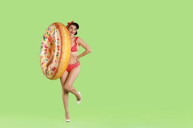 Photo of Pin-up woman in bikini with inflatable ring on green background, space for text