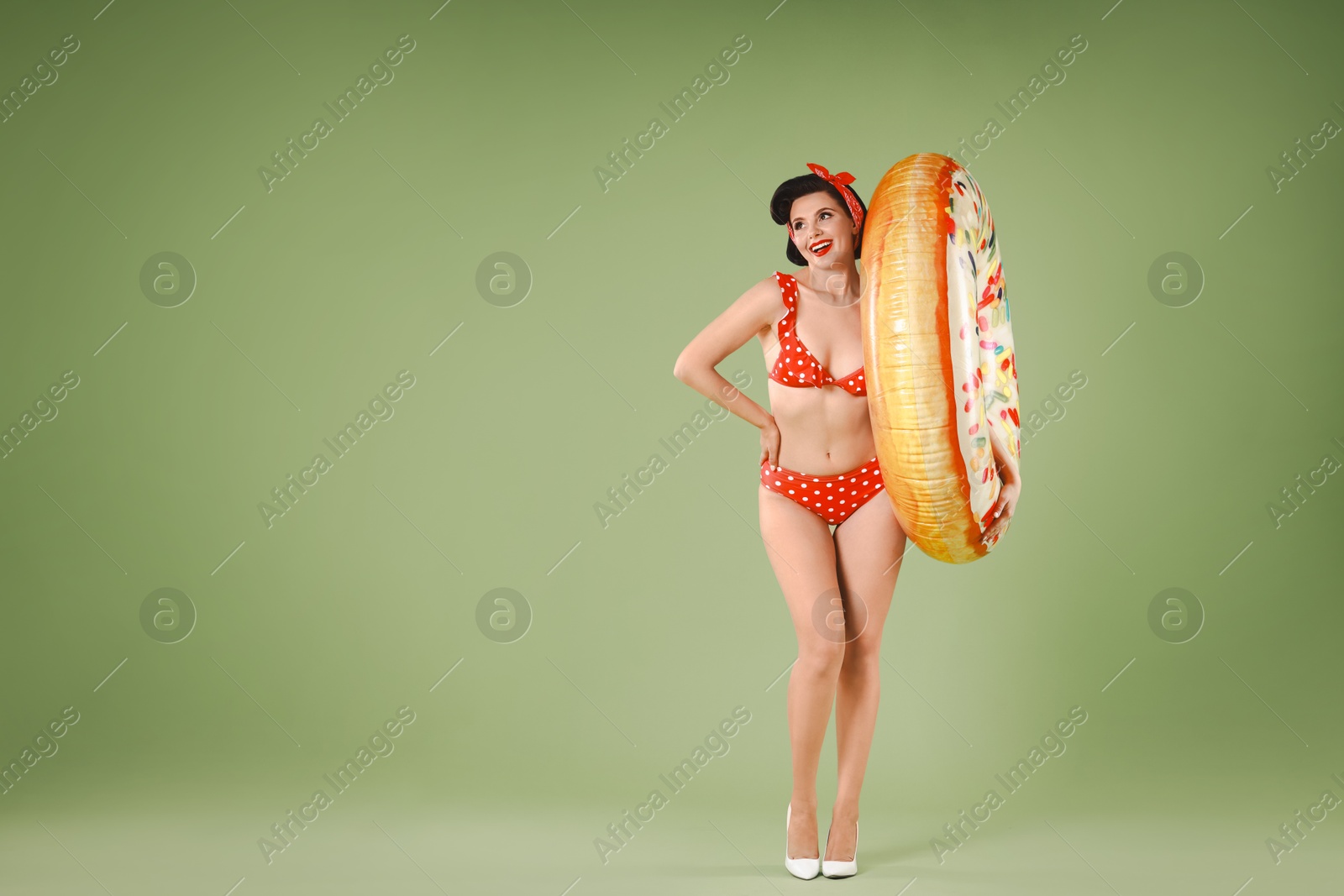 Photo of Pin-up woman in bikini with inflatable ring on green background, space for text