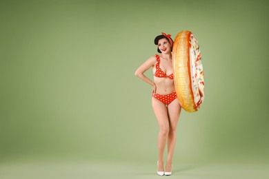 Photo of Pin-up woman in bikini with inflatable ring on green background, space for text