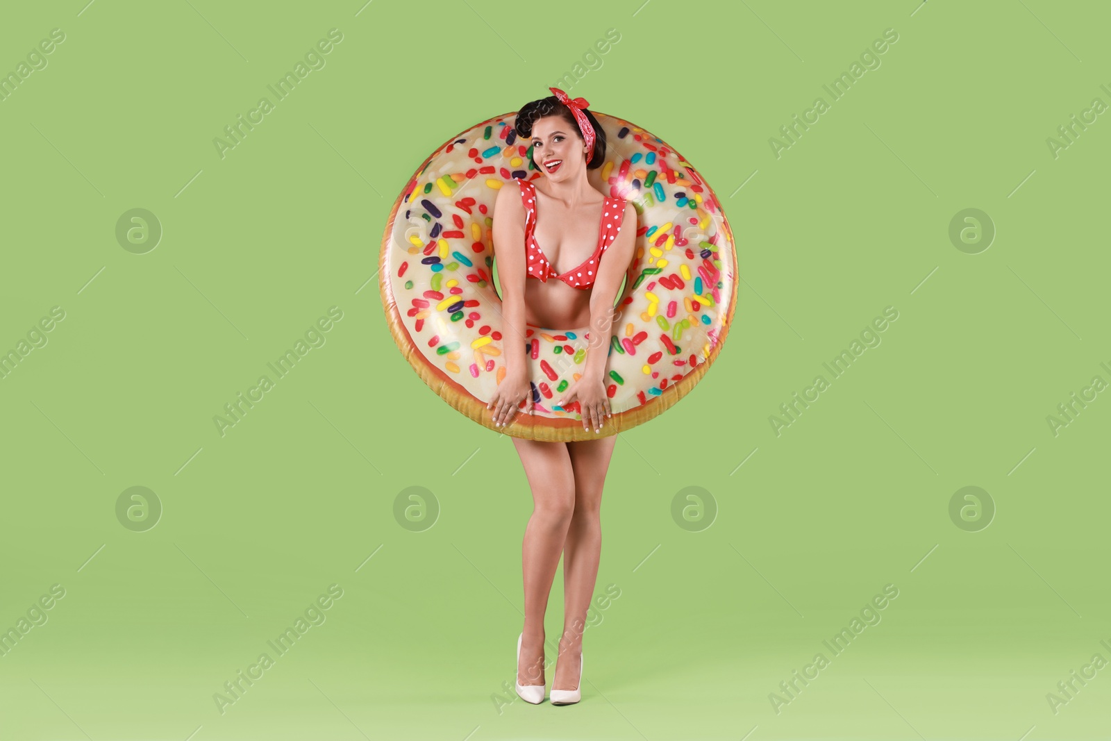 Photo of Pin-up woman in bikini with inflatable ring on green background