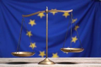 Scales of justice on wooden table against European Union flag