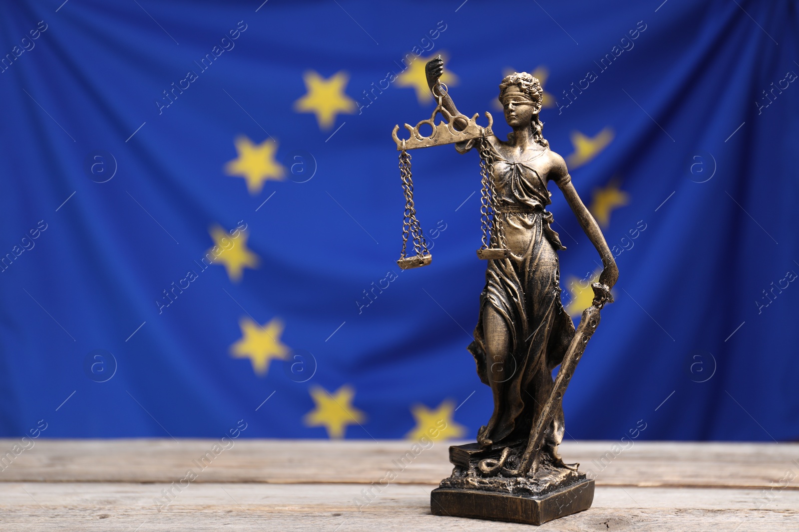 Photo of Figure of Lady Justice on wooden table against European Union flag, space for text