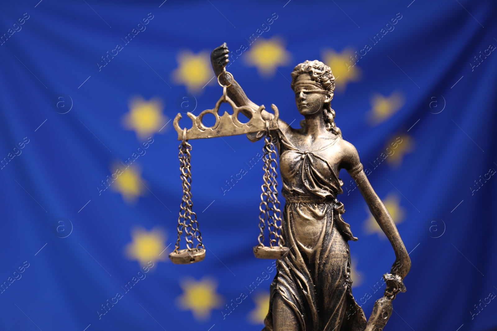 Photo of Figure of Lady Justice against European Union flag, closeup