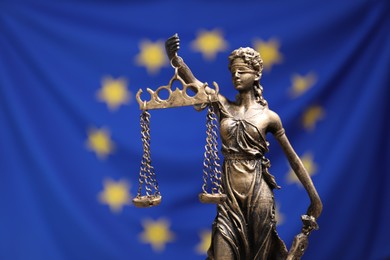 Photo of Figure of Lady Justice against European Union flag, closeup