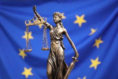 Figure of Lady Justice against European Union flag, closeup