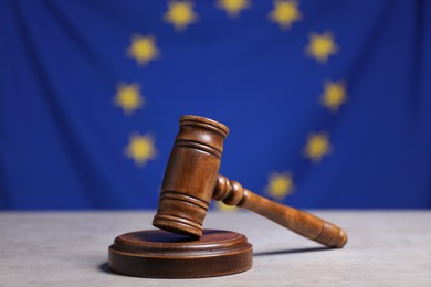 Judge's gavel on grey table against European Union flag, closeup