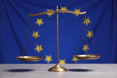 Photo of Scales of justice on table against European Union flag