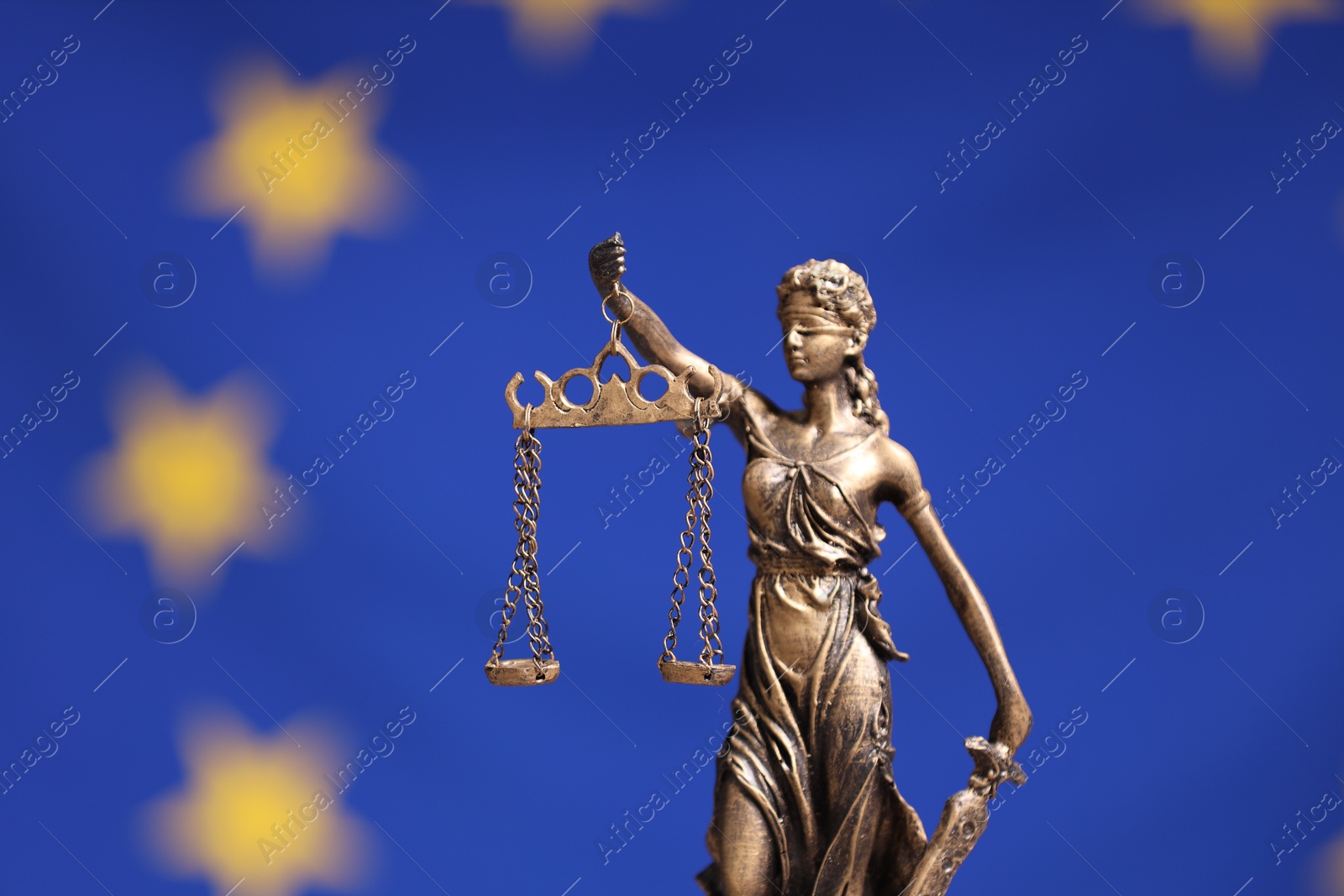 Photo of Figure of Lady Justice against European Union flag, closeup