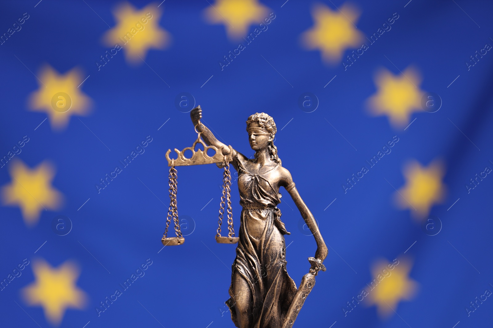 Photo of Figure of Lady Justice against European Union flag, closeup