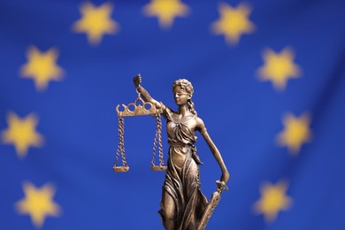 Photo of Figure of Lady Justice against European Union flag, closeup