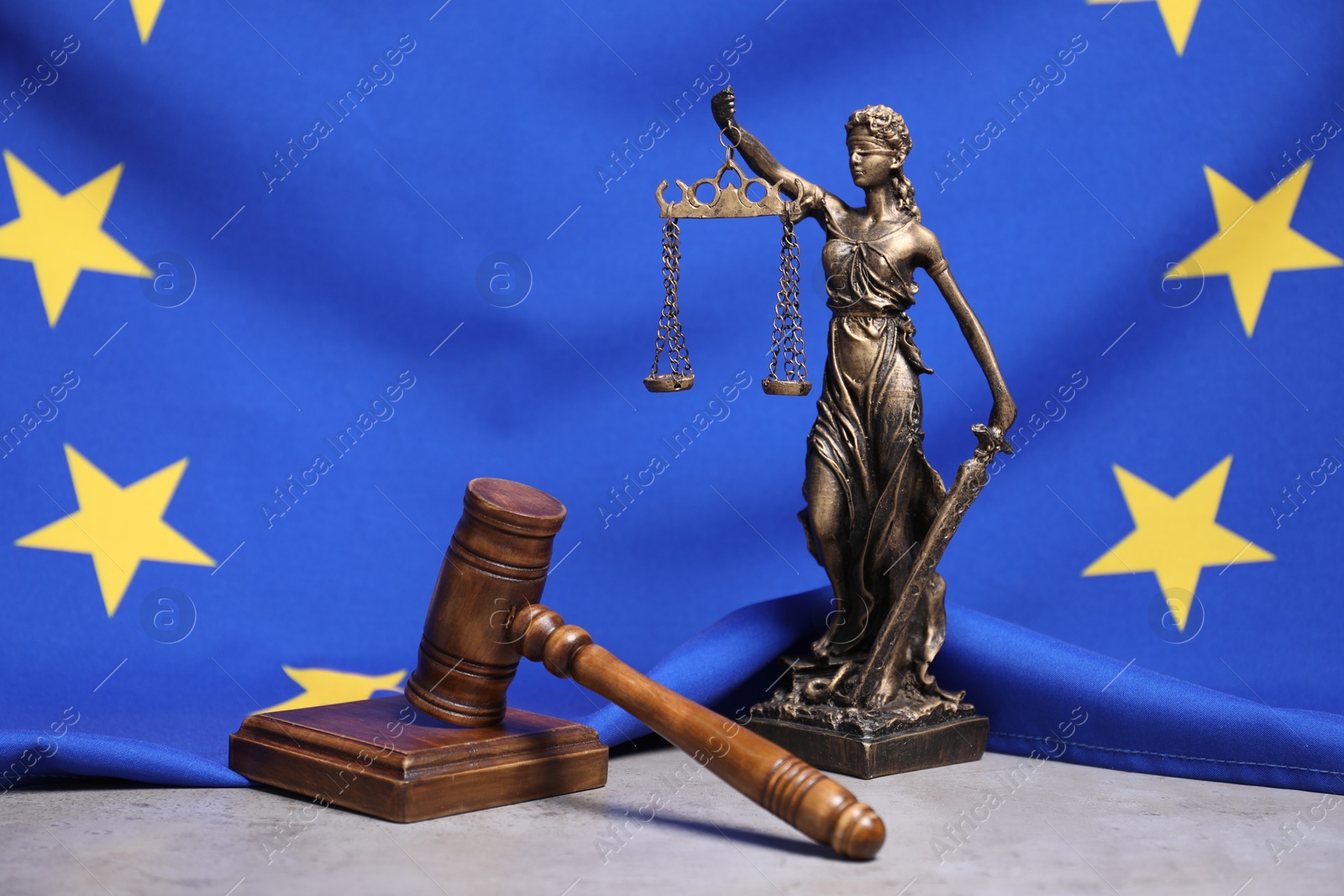 Photo of Figure of Lady Justice, judge's gavel and European Union flag on grey table