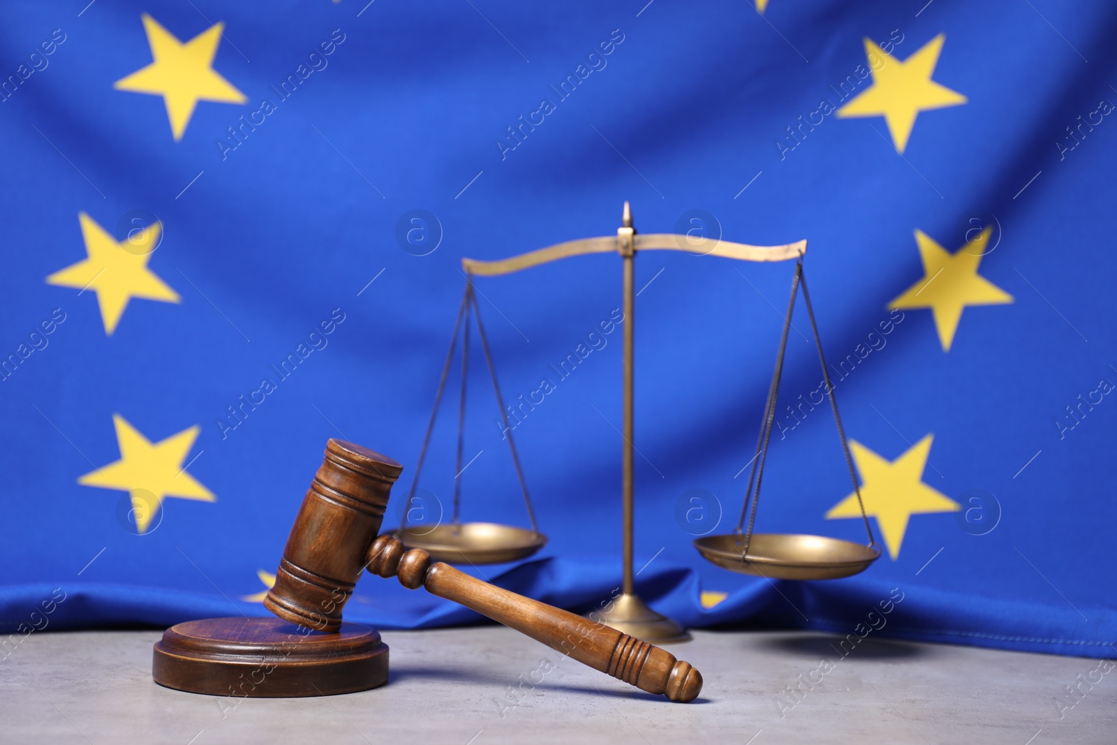 Photo of Judge's gavel, scales and European Union flag on grey table