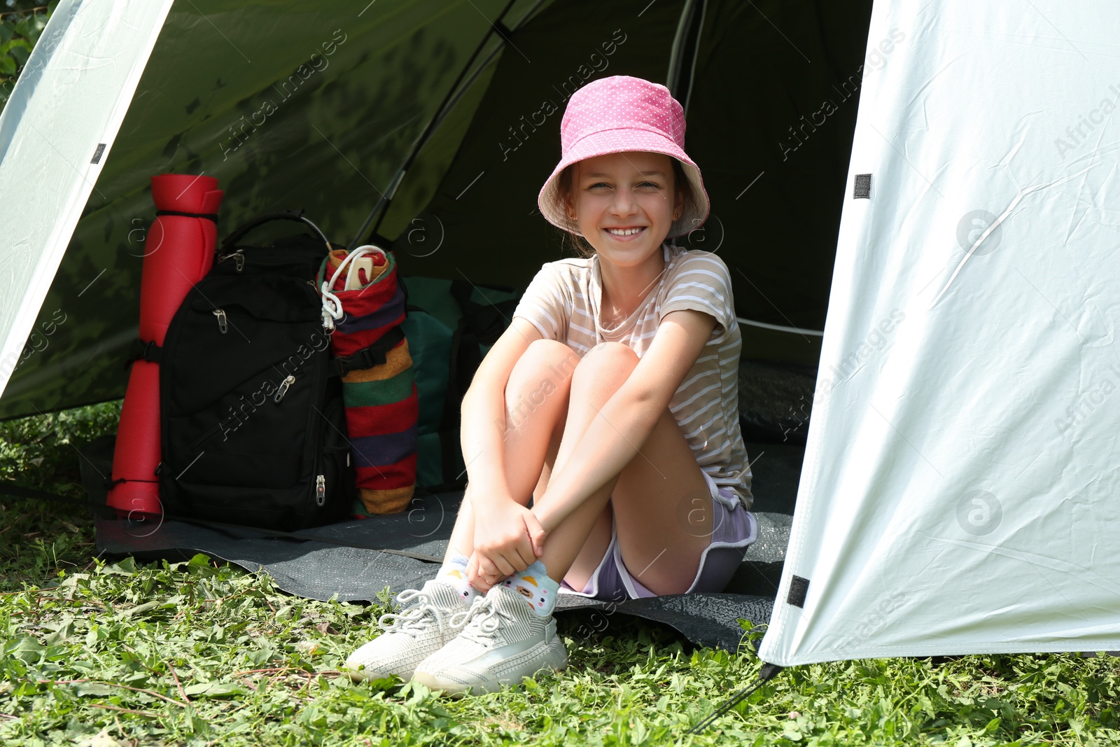 Photo of Cute girl sitting in camping tent outdoors