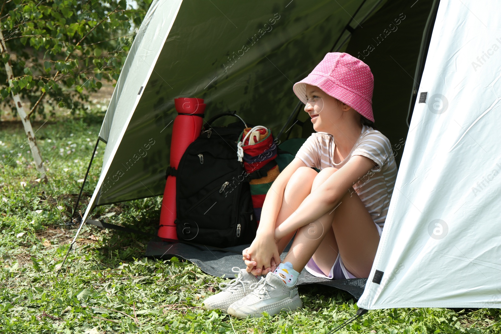 Photo of Cute girl sitting in camping tent outdoors