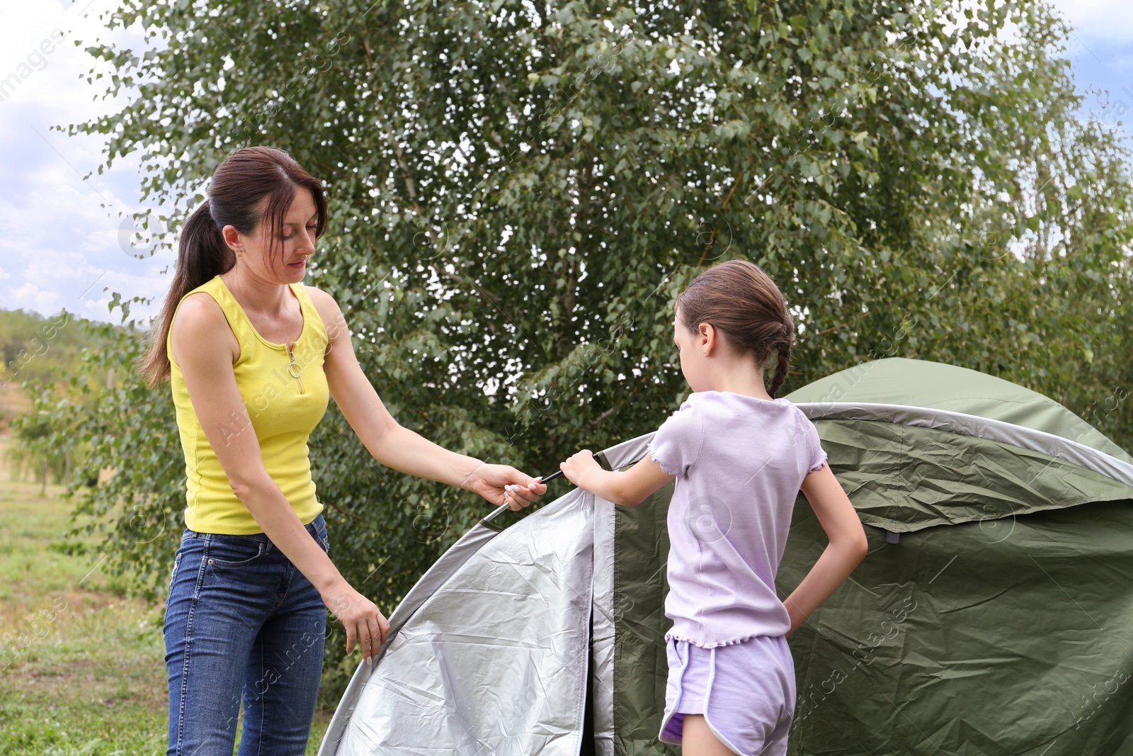 Photo of Mother and her daughter setting up camping tent outdoors