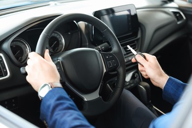 Man with key inside new car in salon, closeup